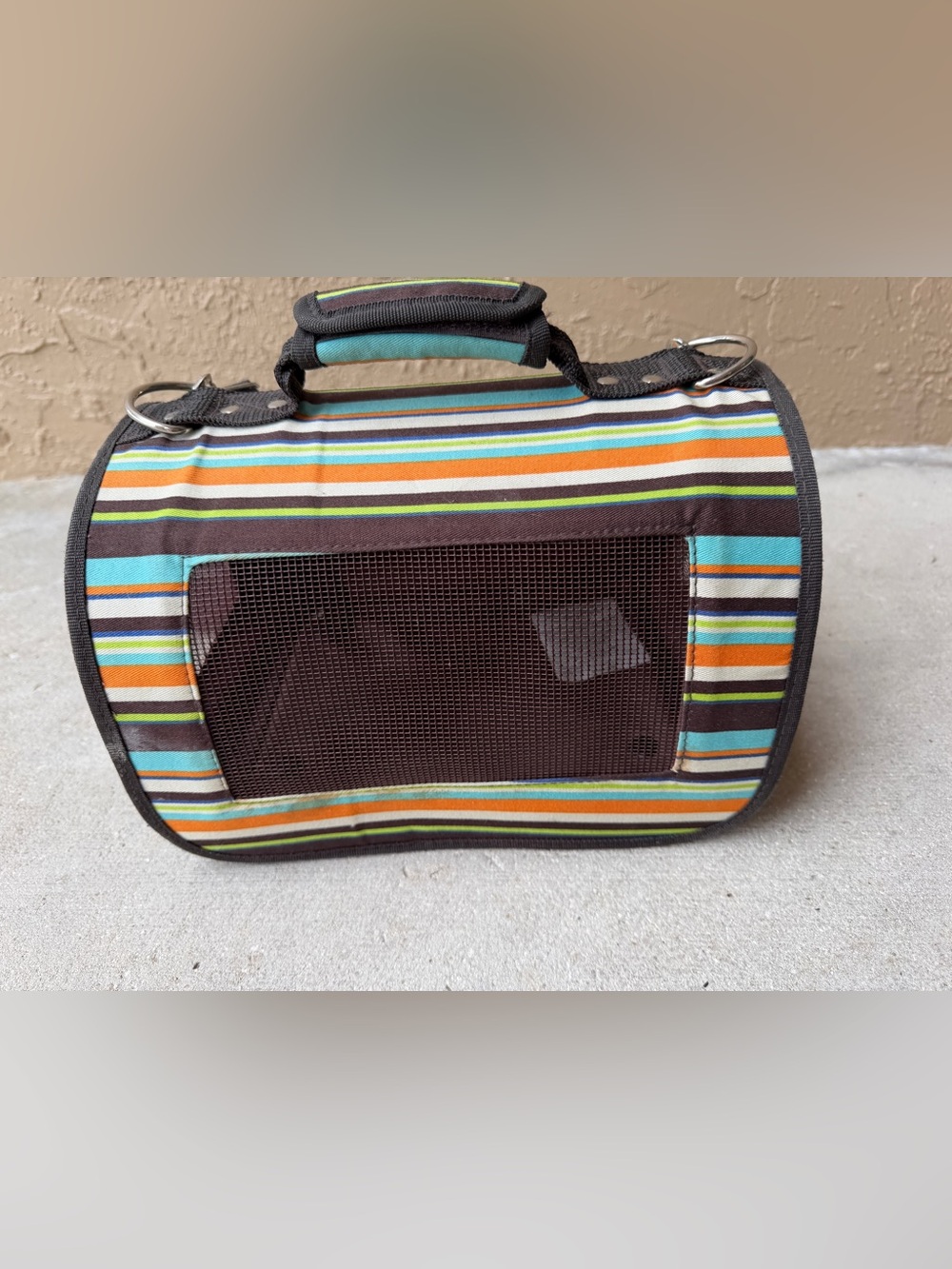 Soft-sided pet carrier featuring multi-colored stripes and mesh ventilation